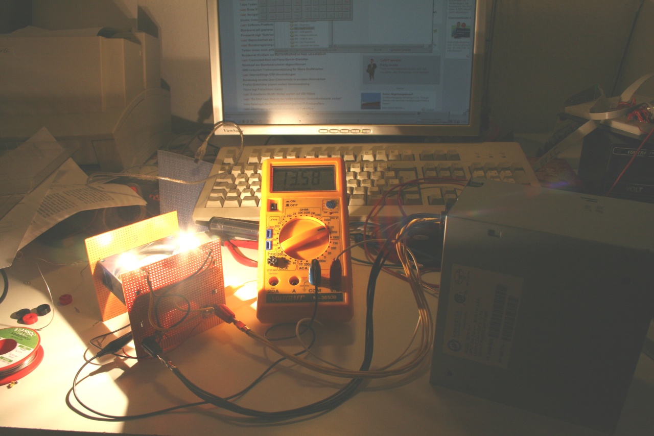 ...im Betrieb, Last 128W effektiv, Ausgangsspannung 13,58V, Bild aufgehellt, da die Lampen alles überstrahlen :-)