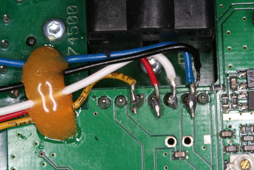 Die Abgänge hinter der DIN-Buchse: blau und weiss führen zum Schalter, so wird die Brücke erzeugt um das 35 MHZ HF Modul auszuschalten<br />schwaz (ebenfalls wie blau an der Masse), rot (+ pol, wenn Cockpit Hauptschalter auf ein ist er aktiv) und gelb (signal/impuls) führen zum Jeti 2.4 GHZ Modul<br />Gut zu erkennen, die Epoxid-Zugentlastung der Lotstellen<br />Übrigens die ganze Löterei sollte nicht nach 5 Tassen Kaffe durchgeführt werden